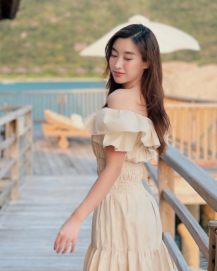 Đỗ Mỹ Linh cũng rất ưa chuộng đầm trễ vai lụa pastel, kết hợp tay áo rộng buông rũ, vừa che khuyết điểm bắp tay sau sinh, vừa tạo cảm giác bay bổng khi gió biển thổi qua. Phần cổ trễ vừa đủ để lộ một chút khe ngực tự nhiên, nhưng không sâu đến mức phản cảm, phù hợp với hình ảnh bà mẹ một con đang xây dựng. Ảnh: FBNV